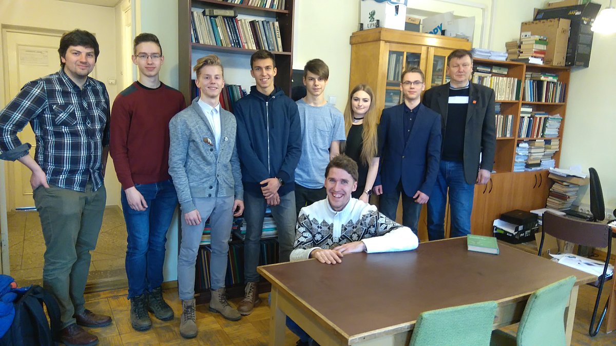Ēnu dienas dalībnieki, apmeklējot Magnētisku mīkstu materiālu laboratoriju apvienojas kopbildē ar laboratorijas pētniekiem un fakultātes dekānu asoc. prof. Sandri Lāci.